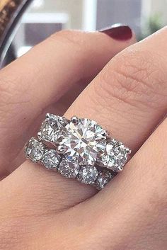 a woman's hand with two engagement rings on it and the ring is in front of her face