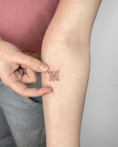 a person with a small tattoo on their arm holding onto her hand and looking at the camera