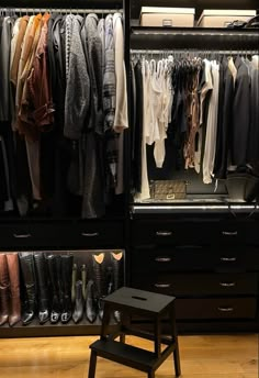 an organized closet with clothes and shoes on the shelves, along with a small stool