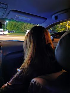 a woman sitting in the passenger seat of a car with her back to the camera