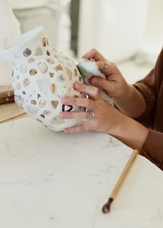 a woman is working on a ceramic vase