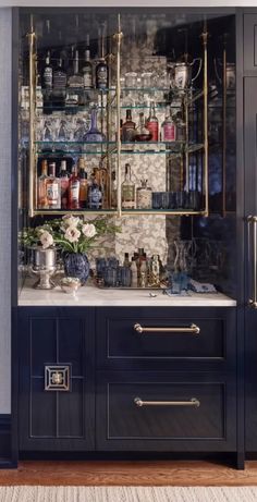 a bar with lots of bottles and glasses on the shelves in front of it's doors