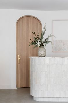 a vase filled with flowers sitting on top of a counter next to a wooden door