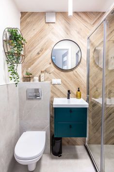 a white toilet sitting under a bathroom mirror next to a sink and a shower stall