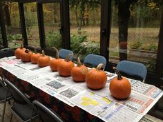 there are many pumpkins sitting on the table in front of the window and newspaper