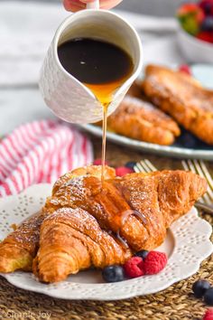 croissants are being drizzled with syrup on a white plate