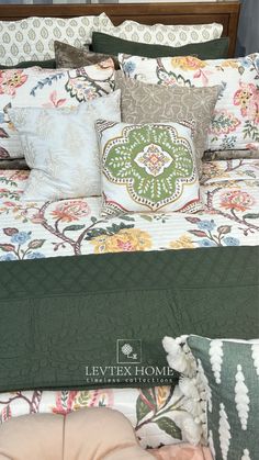 the bed has many pillows on it and is made with green, white, and pink colors