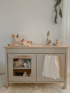 a bathroom with a sink, towel rack and other items on the counter top in front of a white wall