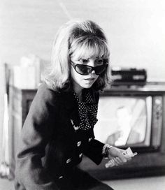 a woman sitting on top of a suitcase in front of an old tv with her hands out