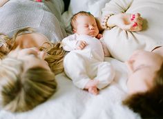 three women and a baby laying on a bed