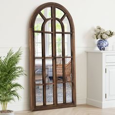 a large arched window in the corner of a room with a chair and potted plant