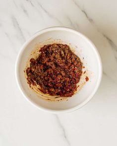 a white bowl filled with food on top of a marble counter