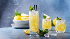 two glasses filled with lemonade and mint garnish next to plates on a table