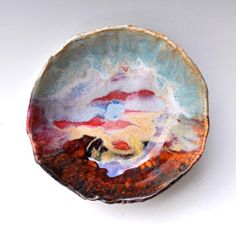 a small bowl is sitting on a white surface with red, yellow and blue designs