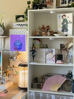 a white bookcase filled with lots of books next to a lamp and pictures on the wall