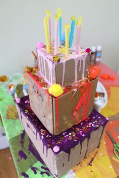 a three tiered cake decorated with candles and sprinkles on a table