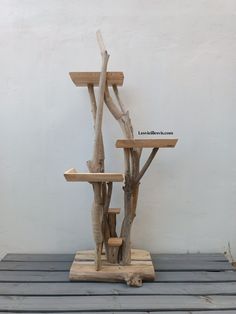 a sculpture made out of branches on top of a wooden platform in front of a white wall