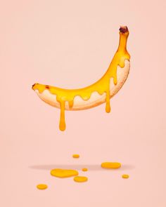 a banana that is dripping yellow paint on it's side and has been placed in the air