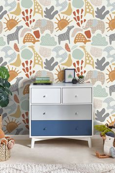 a white dresser sitting next to a colorful wallpaper