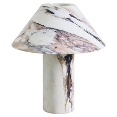 a white marble lamp with a black and brown design on the top, standing upright against a white background