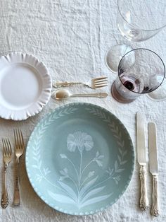 an empty plate and silverware on a white tablecloth with floral designs in the center