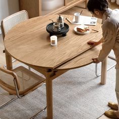 a person standing at a table with food on it and coffee mugs in front of them