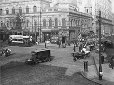 an old black and white photo of people on the street in front of some buildings