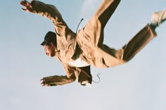 a man flying through the air while riding a skateboard in front of a blue sky