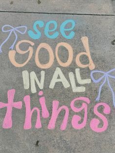 chalk drawing on sidewalk saying see good in all things with pink, blue and purple letters