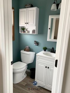 a white toilet sitting in a bathroom next to a sink and cabinet under a mirror