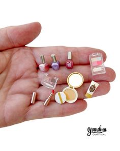 a person's hand holding small miniature nail polishes and makeup products in it