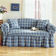 a living room with a blue plaid couch and coffee table in front of the window