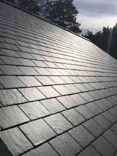 the sun shines brightly on a roof made out of slate tiles, with trees in the background