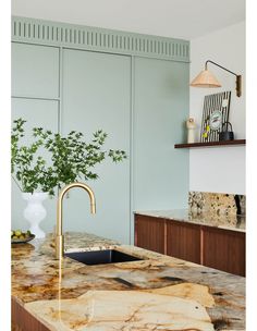 a kitchen with marble counter tops and gold faucet, sink, and cabinets