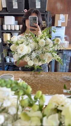 a woman taking a selfie in front of a mirror with flowers on the counter