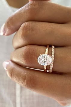 a woman's hand holding a ring with an oval shaped diamond