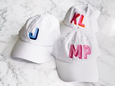 two hats with the letters kl and mp on them sitting on a marble surface