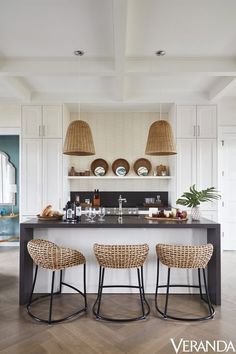 two wicker stools sit in front of an island counter with plates and bowls on it