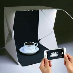 a person is taking a photo with their cell phone and cup on the table in front of them