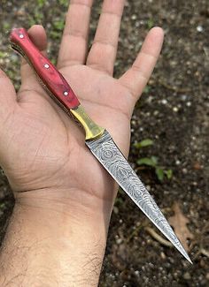 a hand holding a red and yellow knife on top of it's left palm