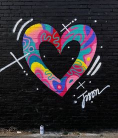 a large heart painted on the side of a brick wall with scissors and other graffiti