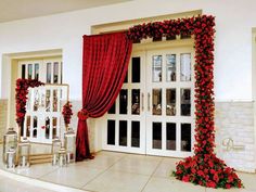 a room decorated with red roses and white doors, windows, and decorations for a wedding