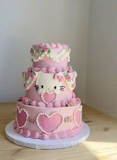 a three tiered cake with hello kitty decorations on it's sides and pink frosting