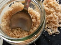 a spoon in a jar filled with sugar and crumbs on top of a table