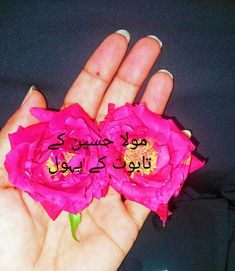 two pink flowers in the palm of someone's hand with arabic writing on it