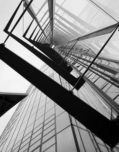 black and white photograph of the side of a tall building with lots of glass on it