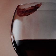 a close up of a wine glass with red wine in it's bottom half