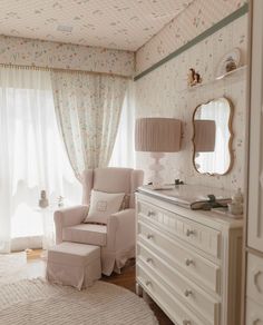 a white chair sitting next to a dresser in a bedroom under a window with curtains