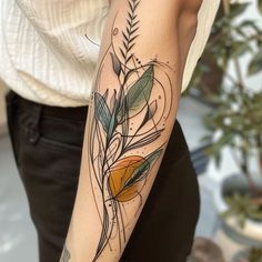 a woman with a tattoo on her arm holding an orange and green leafy branch