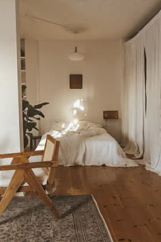 a bed sitting on top of a hard wood floor next to a white curtained wall